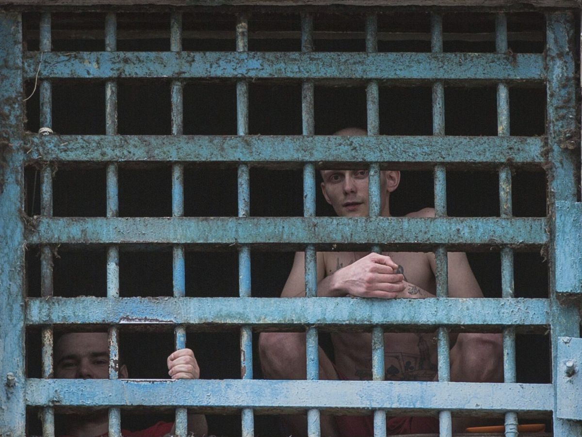Foto: Dos hombres miran a través de los barrotes de su celda. EFE / Roman Pilipey