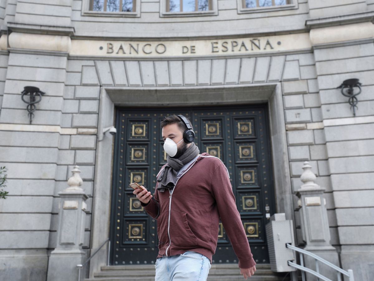 Foto: Un hombre con máscara delante del Banco de España. (Reuters)