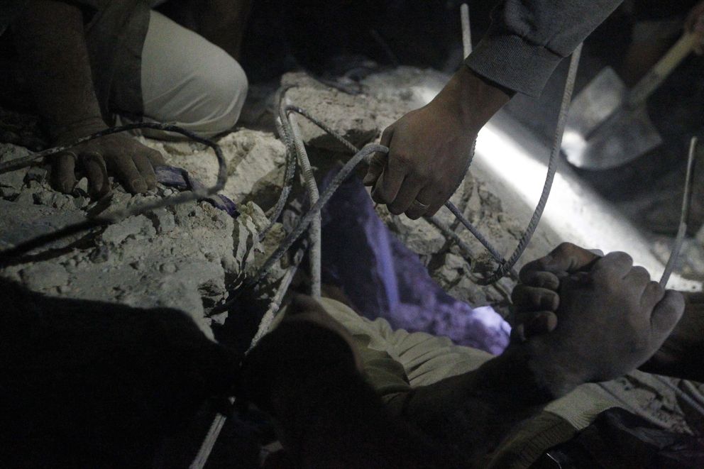 Civiles de Alepo intentan rescatar a un hombre de entre los escombros tras un bombardeo (Reuters).