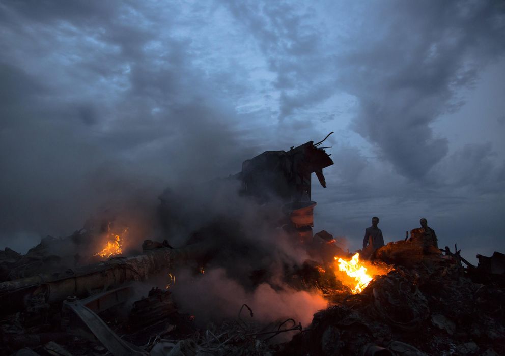 Foto: Un grupo de personas camino entre los restos del avión malasio derribado en el Este de Ucrania (AP).