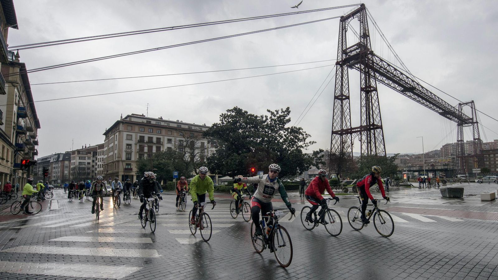 Foto: Un grupo de ciclistas pasa por delante del Puente de Bizkaia en Getxo durante la clásica cicloturista Bilbao-Bilbao. (Efe)