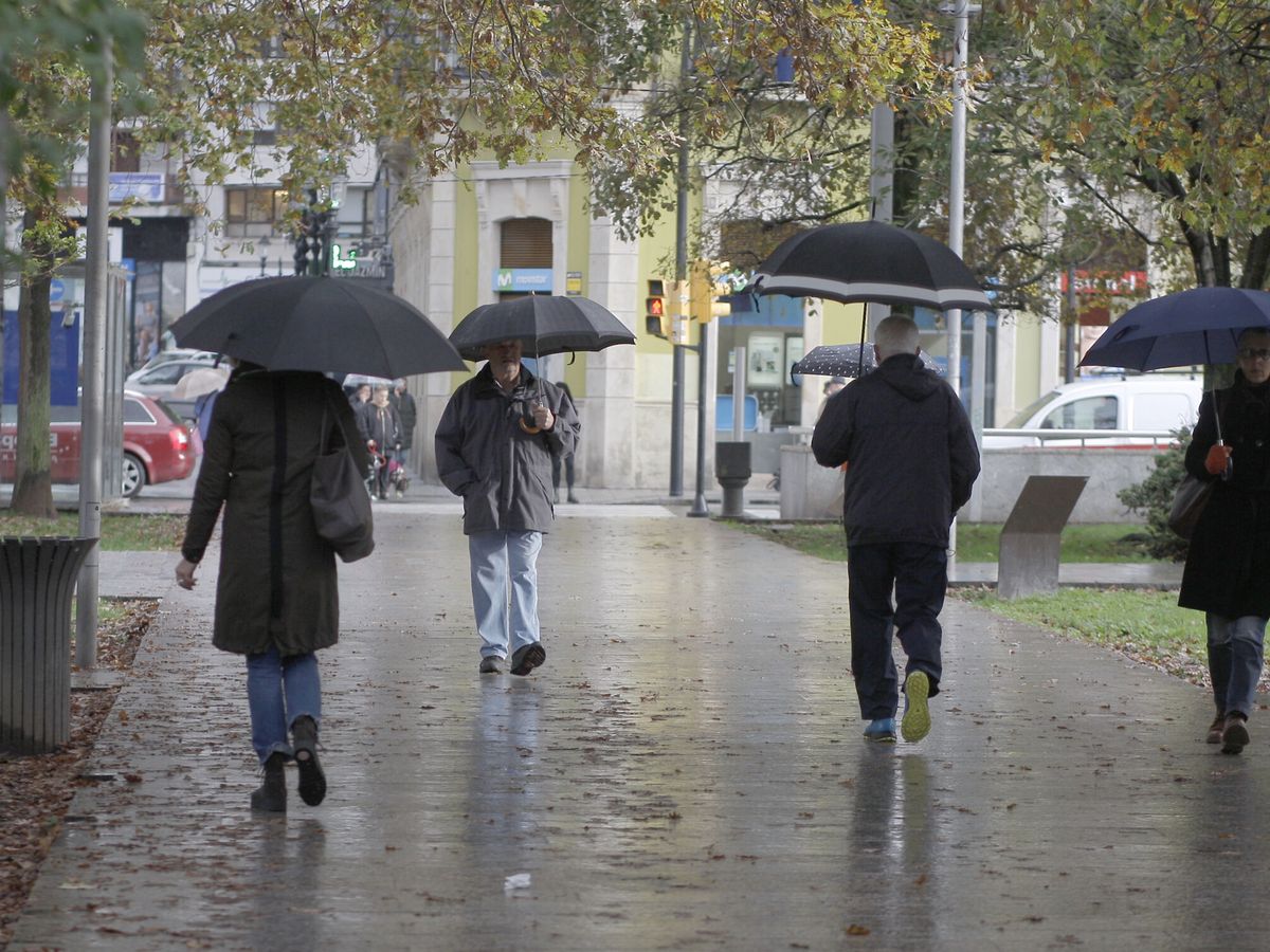 Foto: Un grupo de personas caminan bajo la lluvia en la Plaza de Europa de Gijón. (EFE/Juan González)