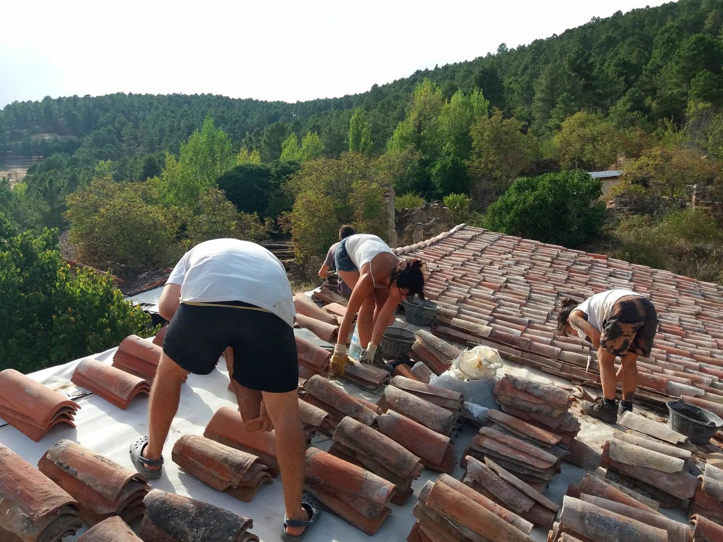 Varias personas construyen el tejado de una de las casas rehabilitadas.