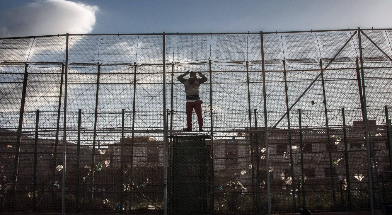 Un migrante subsahariano, en la valla de Melilla tras intentar entrar en territorio español. (Reuters)