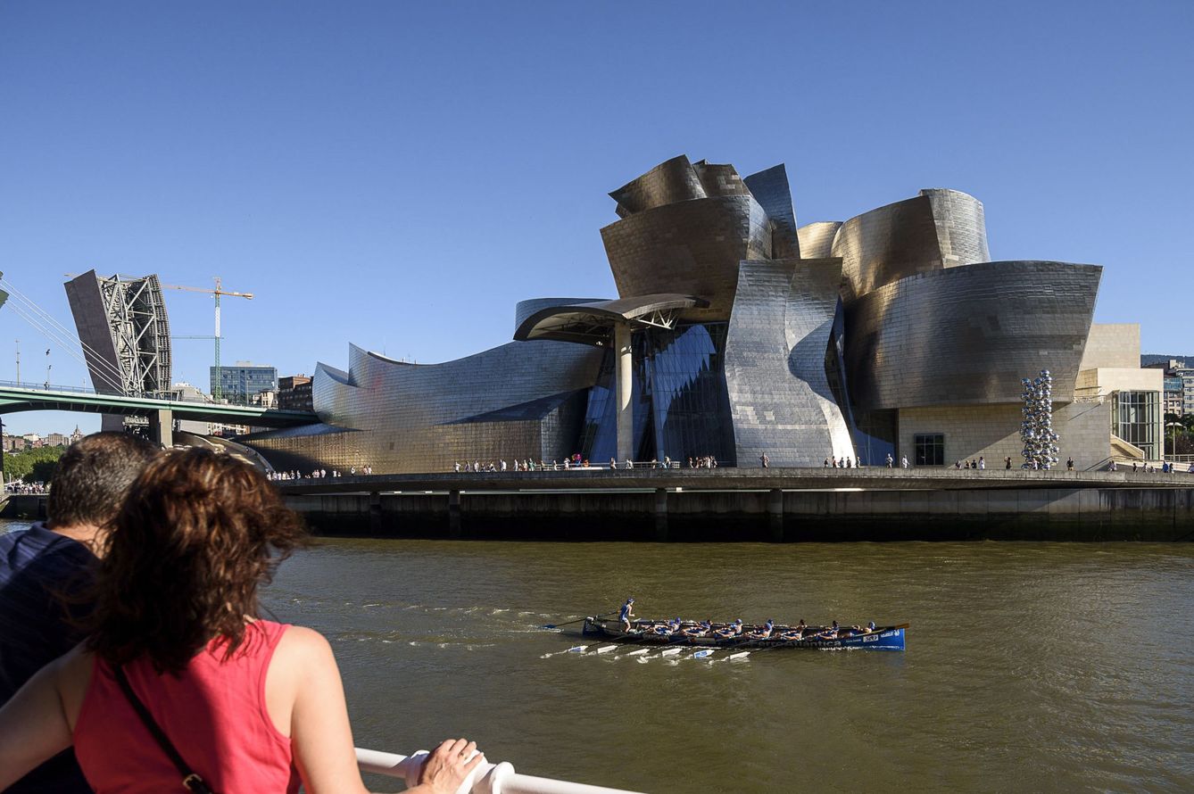Varias personas observan el Museo Guggenheim durante la celebración de la Bandera de Bilbao. (EFE)