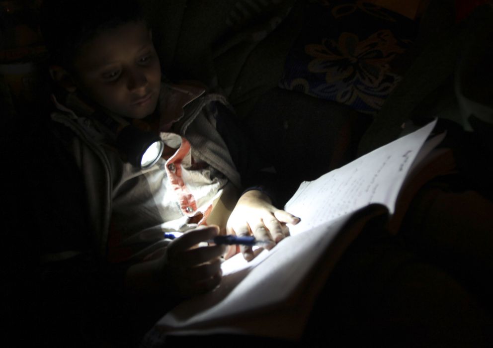 Foto: Un niño lee en la oscuridad con su linterna (Reuters)