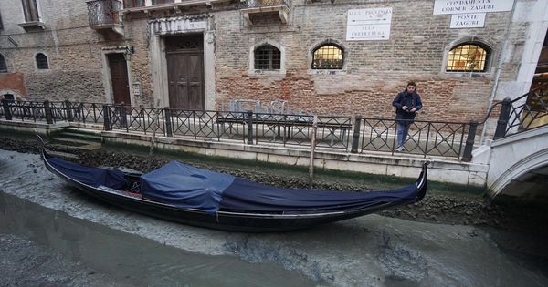 Foto: Una góndola permanece amarrada en un canal prácticamente sin agua en Venecia. (EFE)