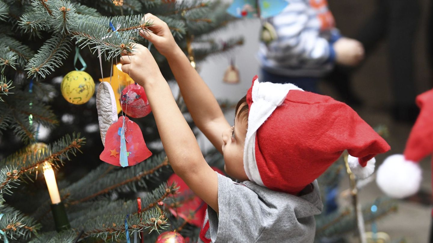 Un niño adorna un árbol de Navidad en una escuela infantil. (EFE)