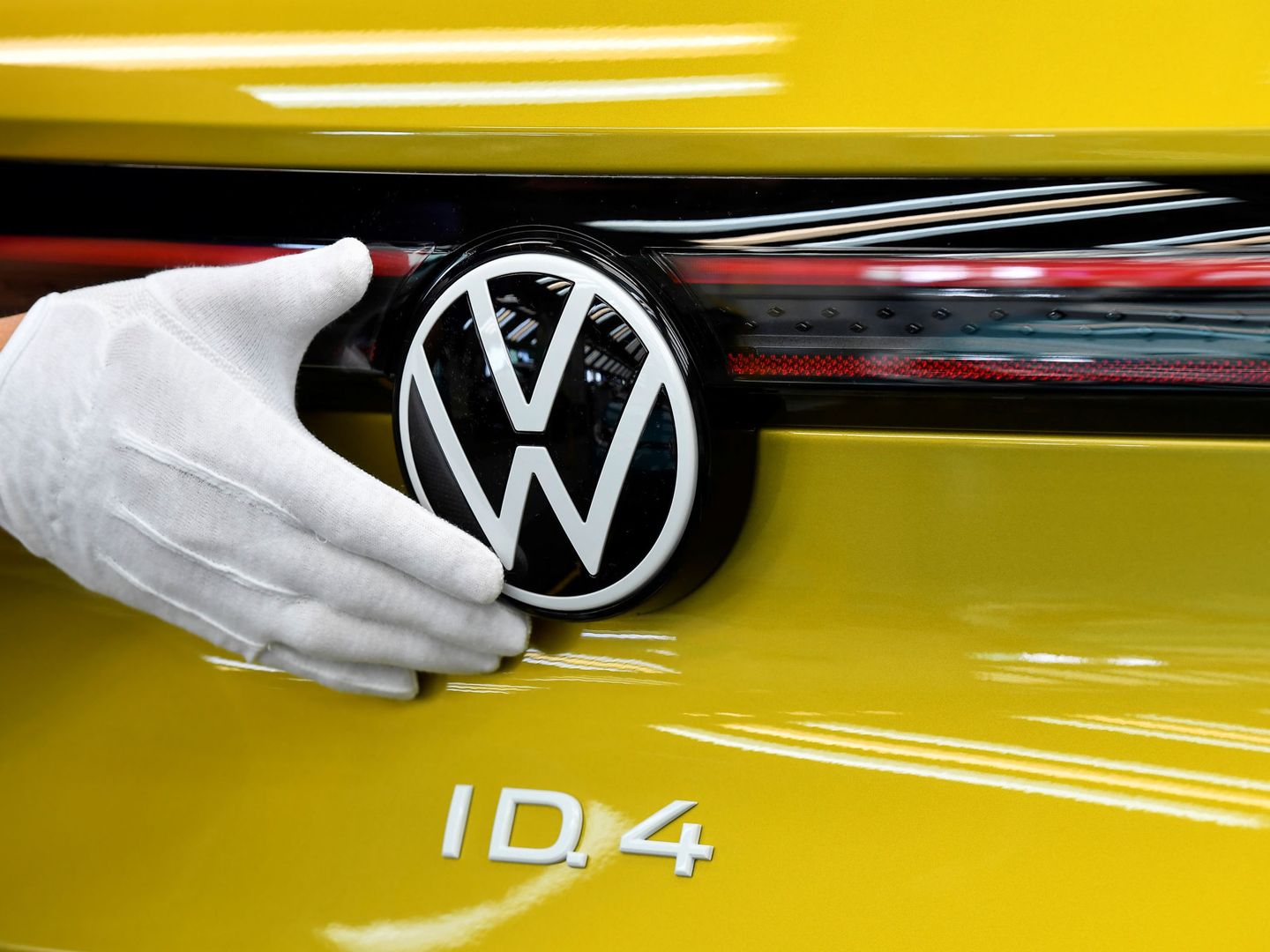 Empleado revisando el logo de Volkswagen en un coche ID.4 (Reuters)