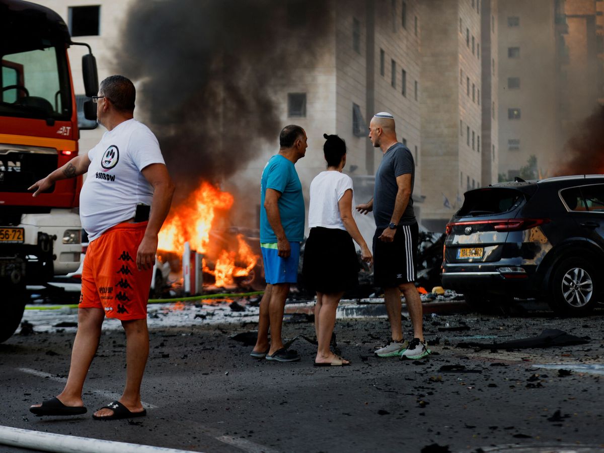 Foto: Ciudadanos israelíes junto a los fuegos provocados por los ataques. (Reuters/Amir Cohen)