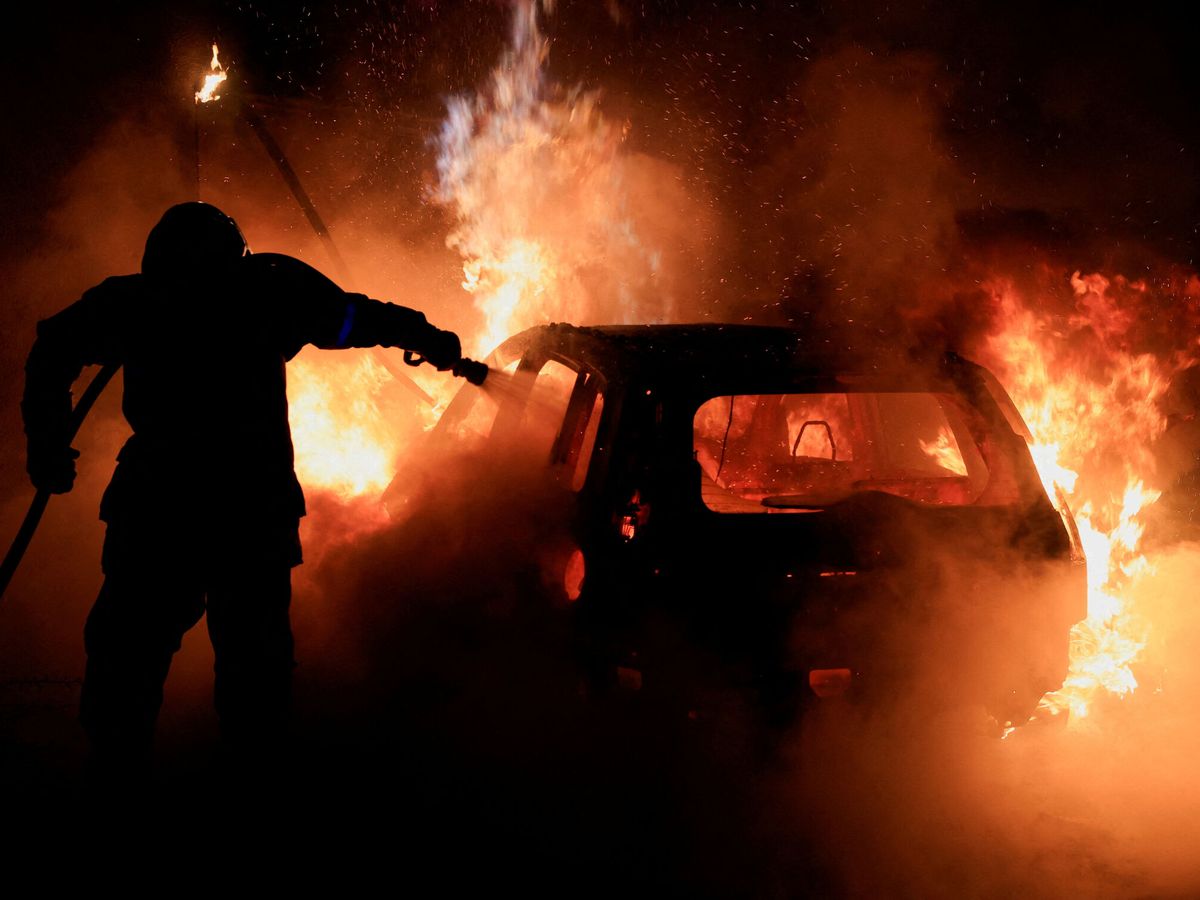 Foto: Un bombero francés intenta extinguir el fuego de un coche ardiendo. (Reuters/Pascal Rossignol)