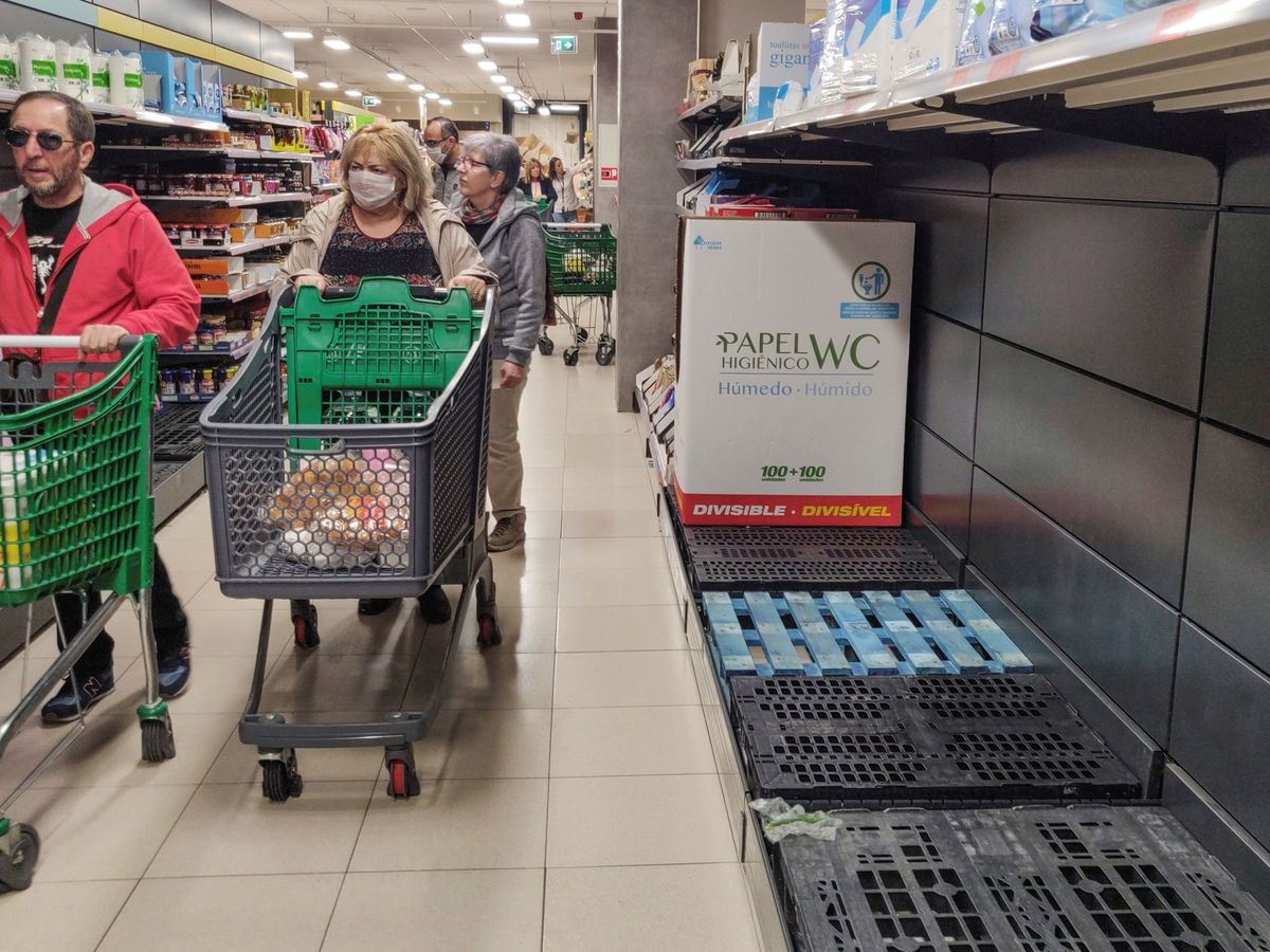 Foto: Una cliente con mascarilla pasa junto a estantes vacíos de papel higiénico en un supermercado de Madrid.  (EFE)