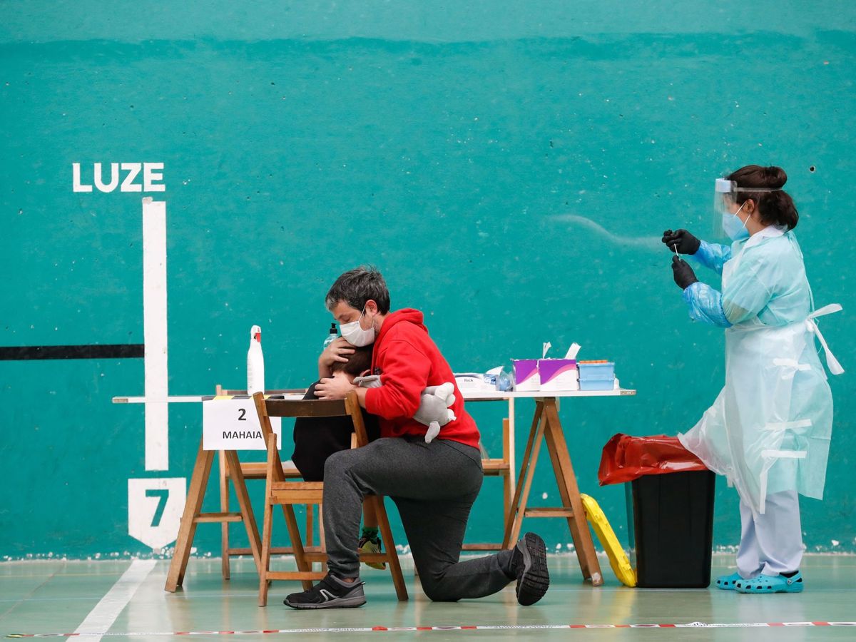 Foto: Un padre consuela a su hijo tras someterse a la prueba PCR en Getaria. (EFE)