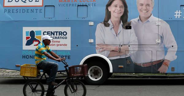 Foto: Un hombre pasa frente a un autobús con publicidad del candidato a la Presidencia de Colombia Iván Duque (d), en Bogotá. (EFE)