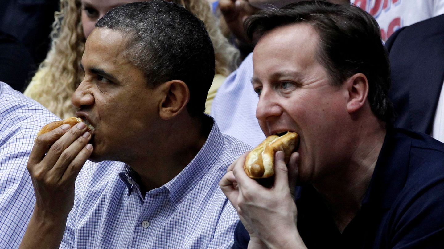 Barack Obama y David Cameron comen un perrito caliente en un partido de baloncesto. (EFE)