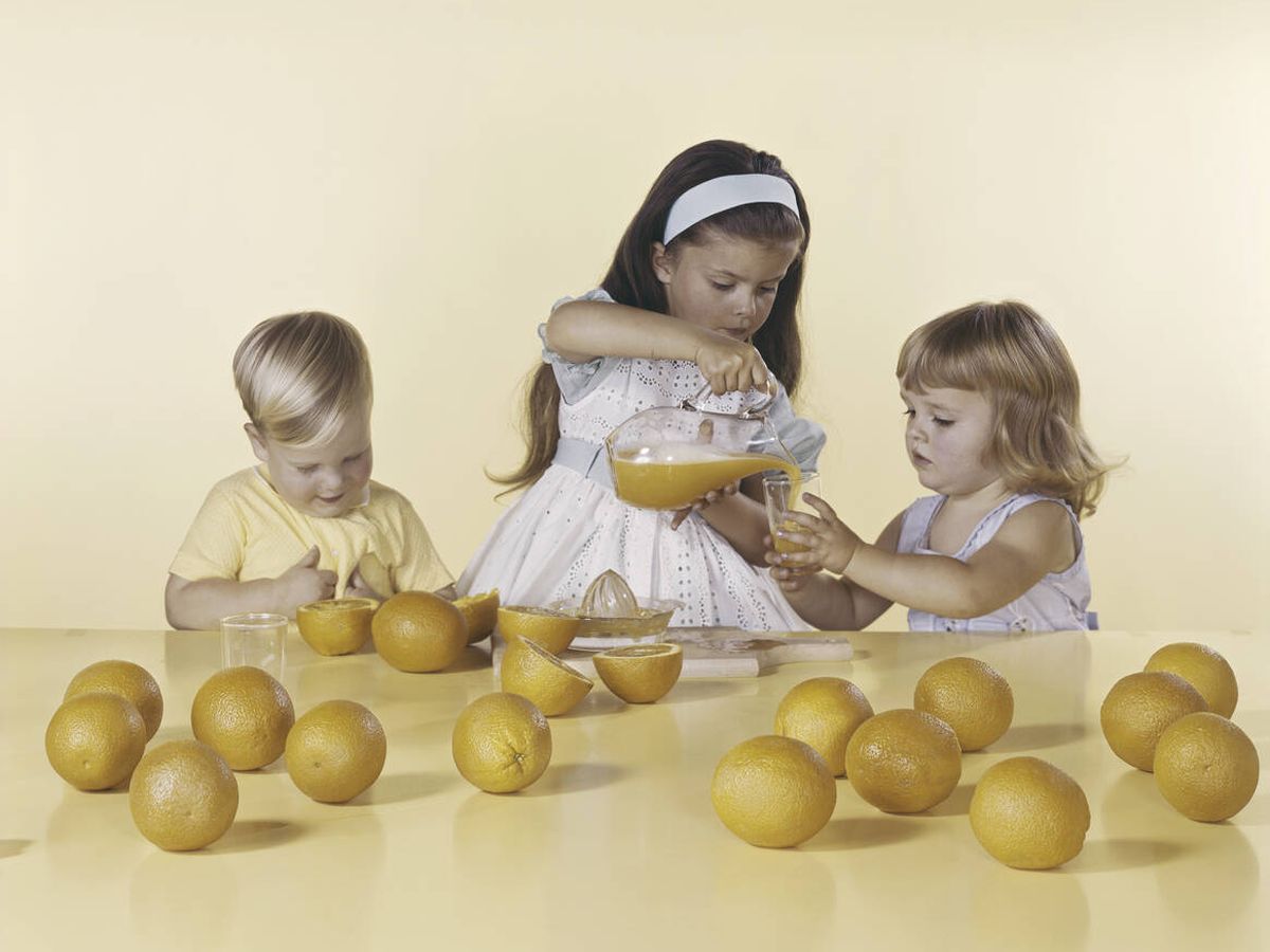 Foto: Unas niñas se sirven limonada recién exprimida con un exprimidor manual de plástico, en los años sesenta. (iStock)