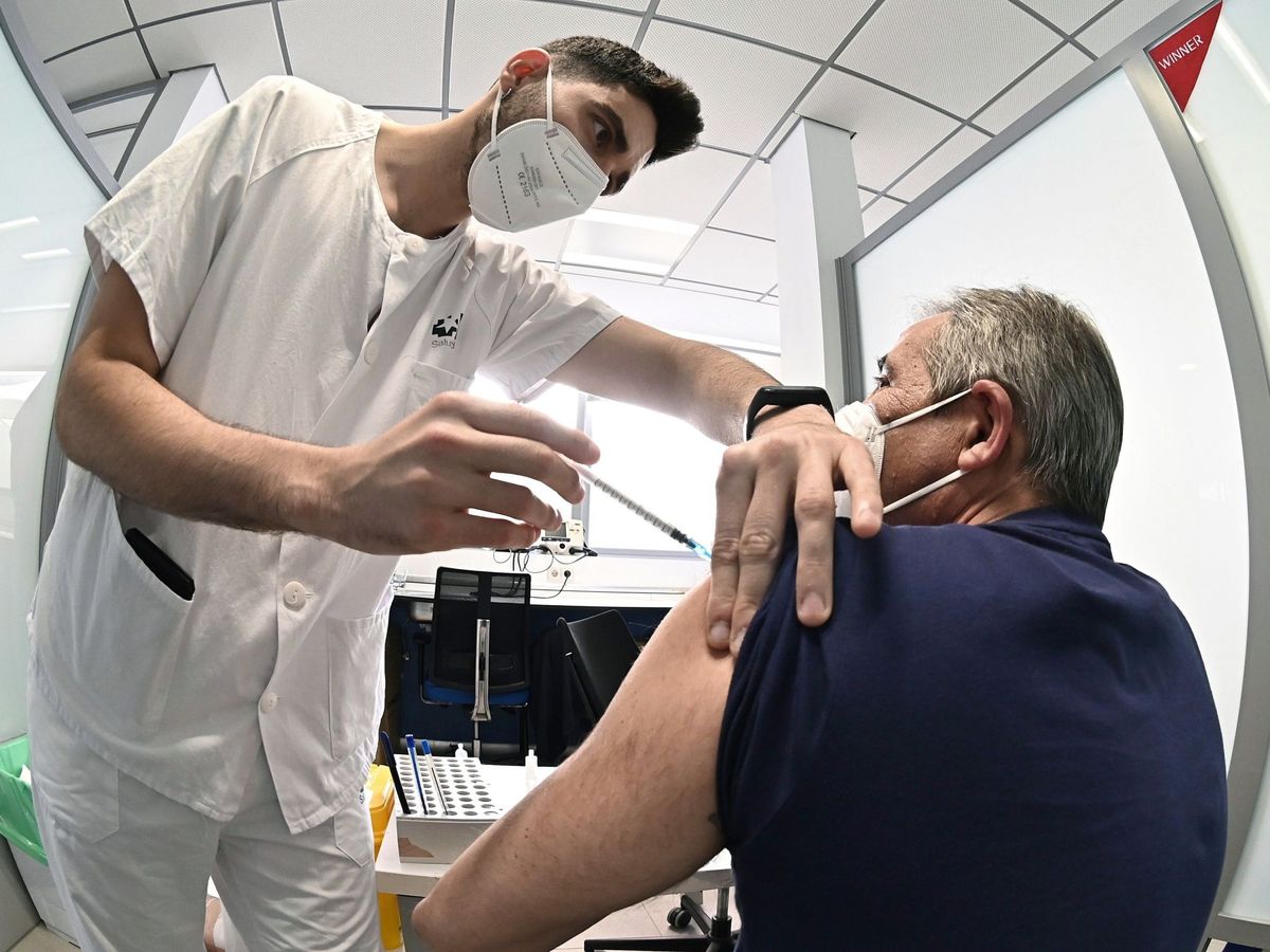 Foto: Un sanitario vacuna contra el coronavirus a un hombre en el hospital de Alcalá de Henares. (EFE)