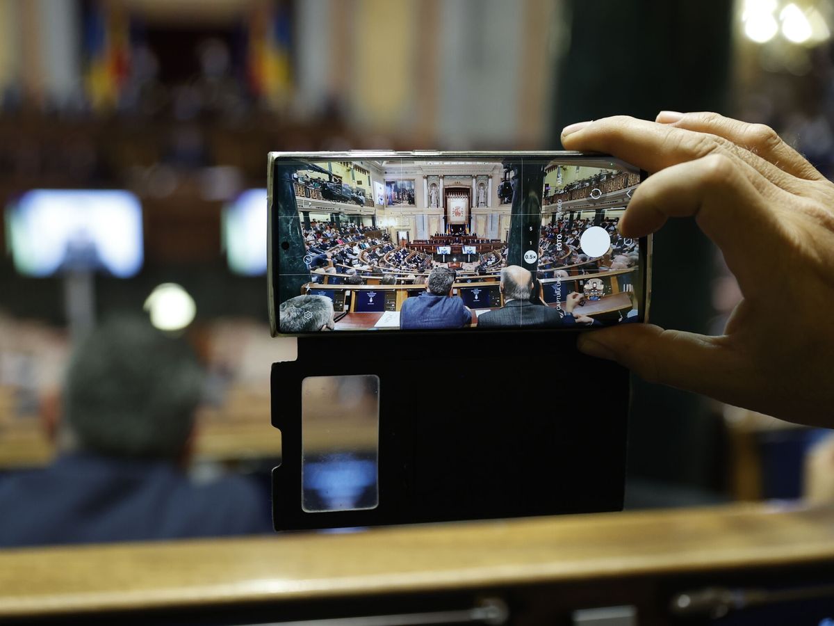 Foto: Un diputado hace una fotografía durante la intervención por videoconferencia del presidente de Ucrania, Volodímir Zelenski. (EFE/Chema Moya)