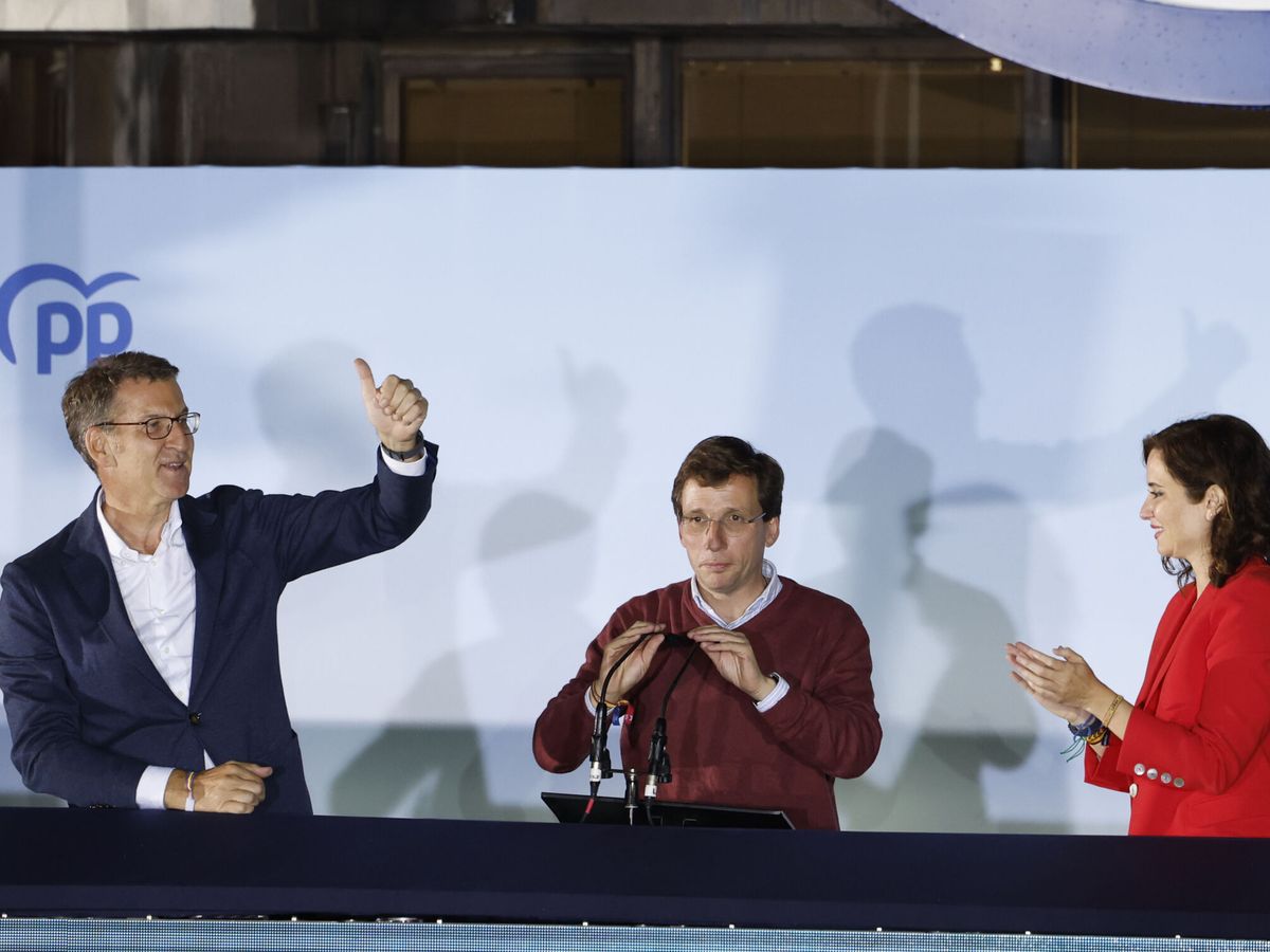 Foto: Feijóo, Almeida y Ayuso saludan a los simpatizantes desde el balcón de Génova. (EFE/Juanjo Martín)