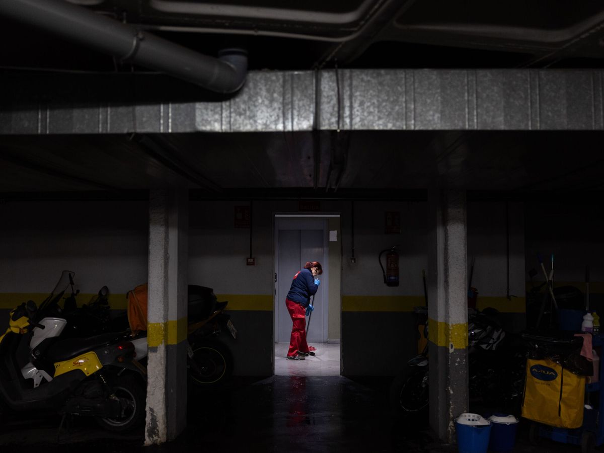 Foto: Una empleada de la limpieza en el garaje donde ha aparecido uno de los cuerpos. (EFE/Daniel González)