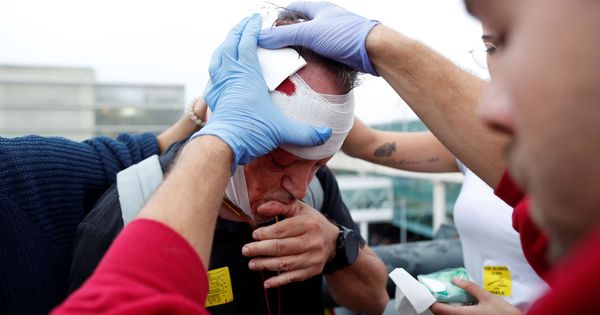 Foto: Un sanitario atiende a un manifestante herido después de las cargas de los Mossos d'Esquadra en El Prat. (EFE)