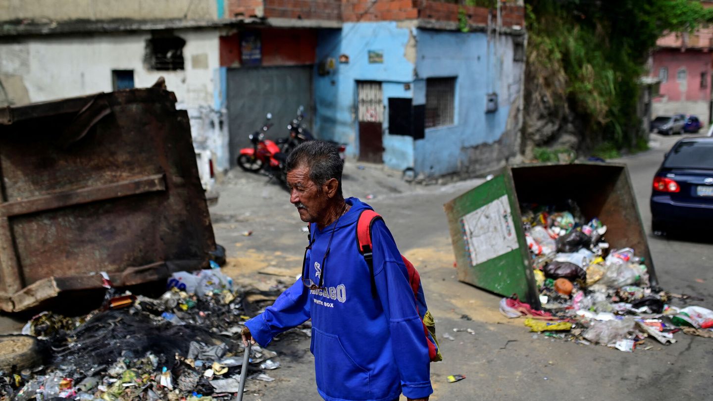 Un hombre pasa junto a contenedores de basura volcados después de que tanto el presidente Nicolás Maduro como su rival opositor Edmundo González se proclamaran vencedores. (Reurers/Maxwell Briceno)