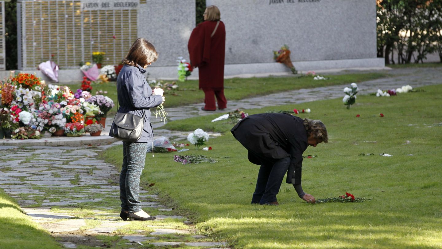 Dos mujeres depositan flores en el Jardín del Recuerdo, del cementerio de la Almudena de Madrid. (EFE)