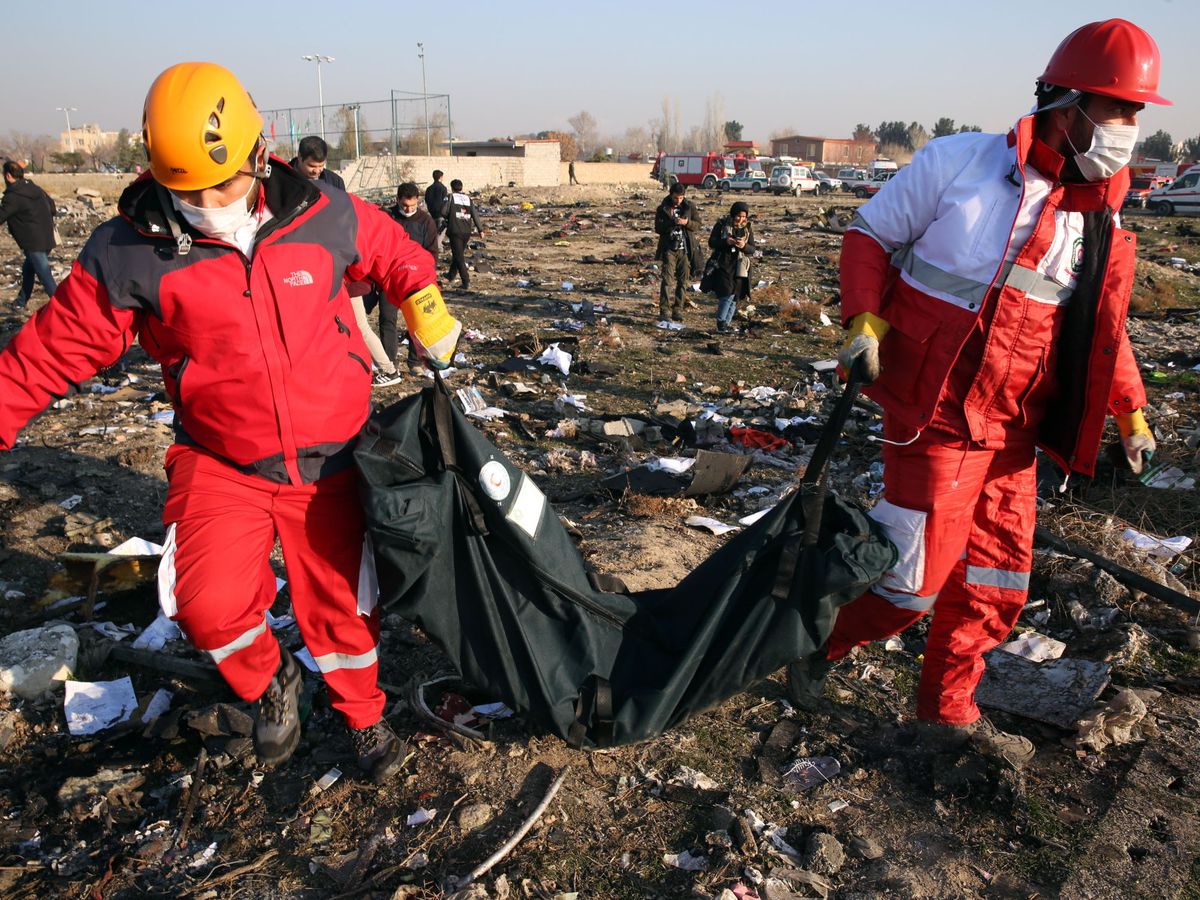 Foto: Miembros de la Media Luna Roja colectan restos tras el accidente de avión cerca de Teherán. (EFE)