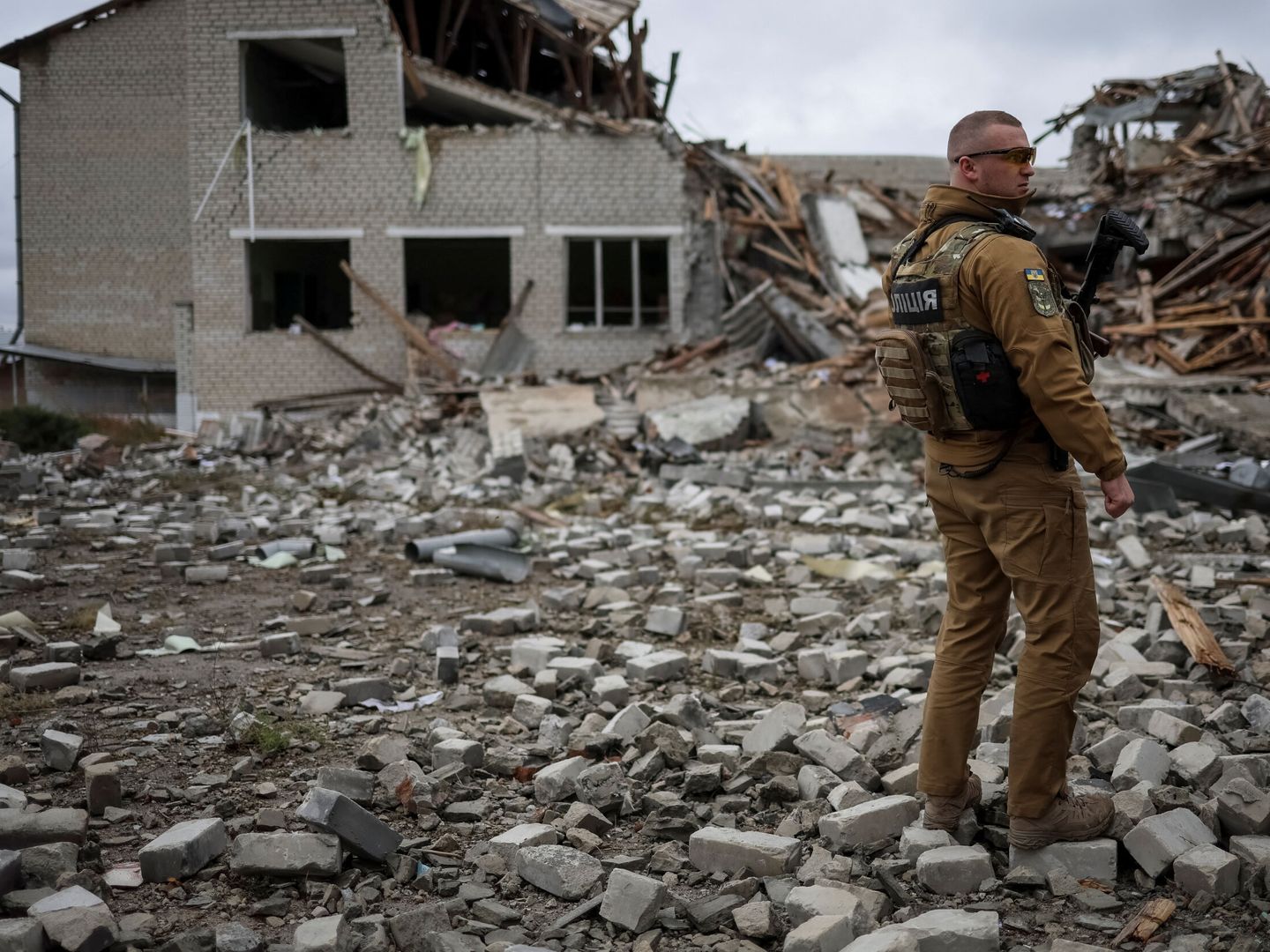 Un policía ucraniano delante del edificio destruido de un colegio en la región de Járkov. (Reuters/Gleb Garanich)