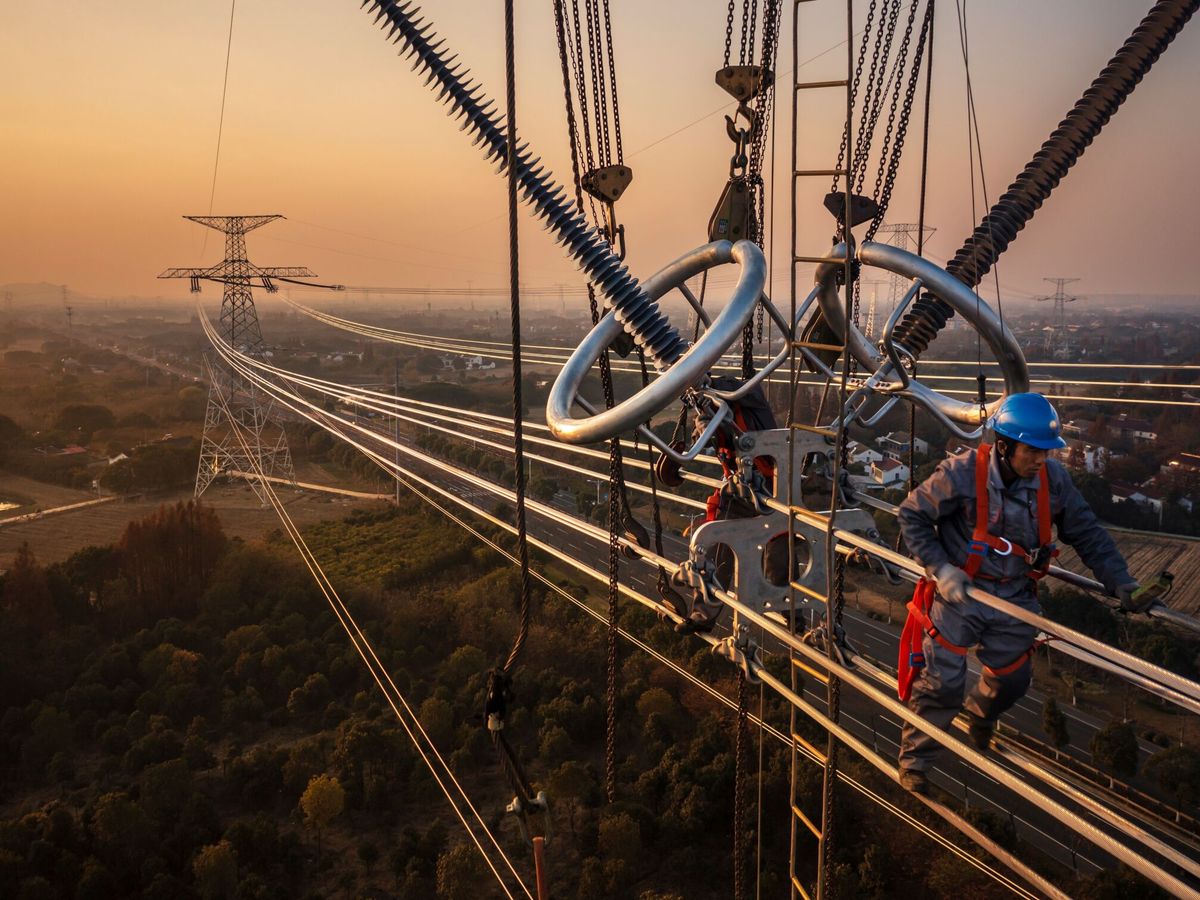 Foto: Trabajadores instalan unas líneas eléctricas en una torre de alta tensión en China. (EFE/Alex Plavevski)