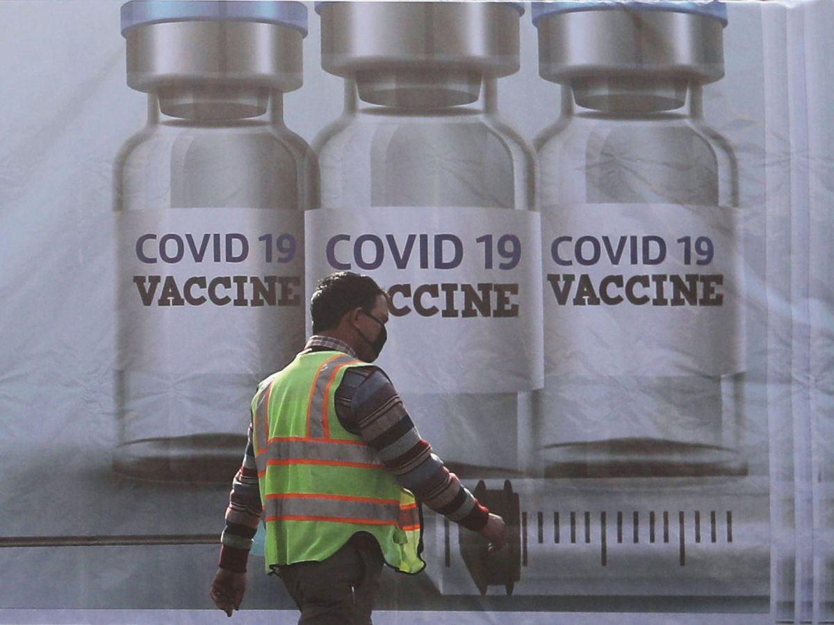 Foto: Trabajador frente a un cartel de las vacunas contra el covid-19. (Reuters)