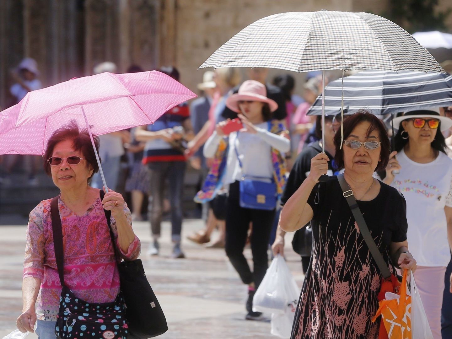 Un grupo de turistas japoneses se protegen del sol con paraguas. (EFE)