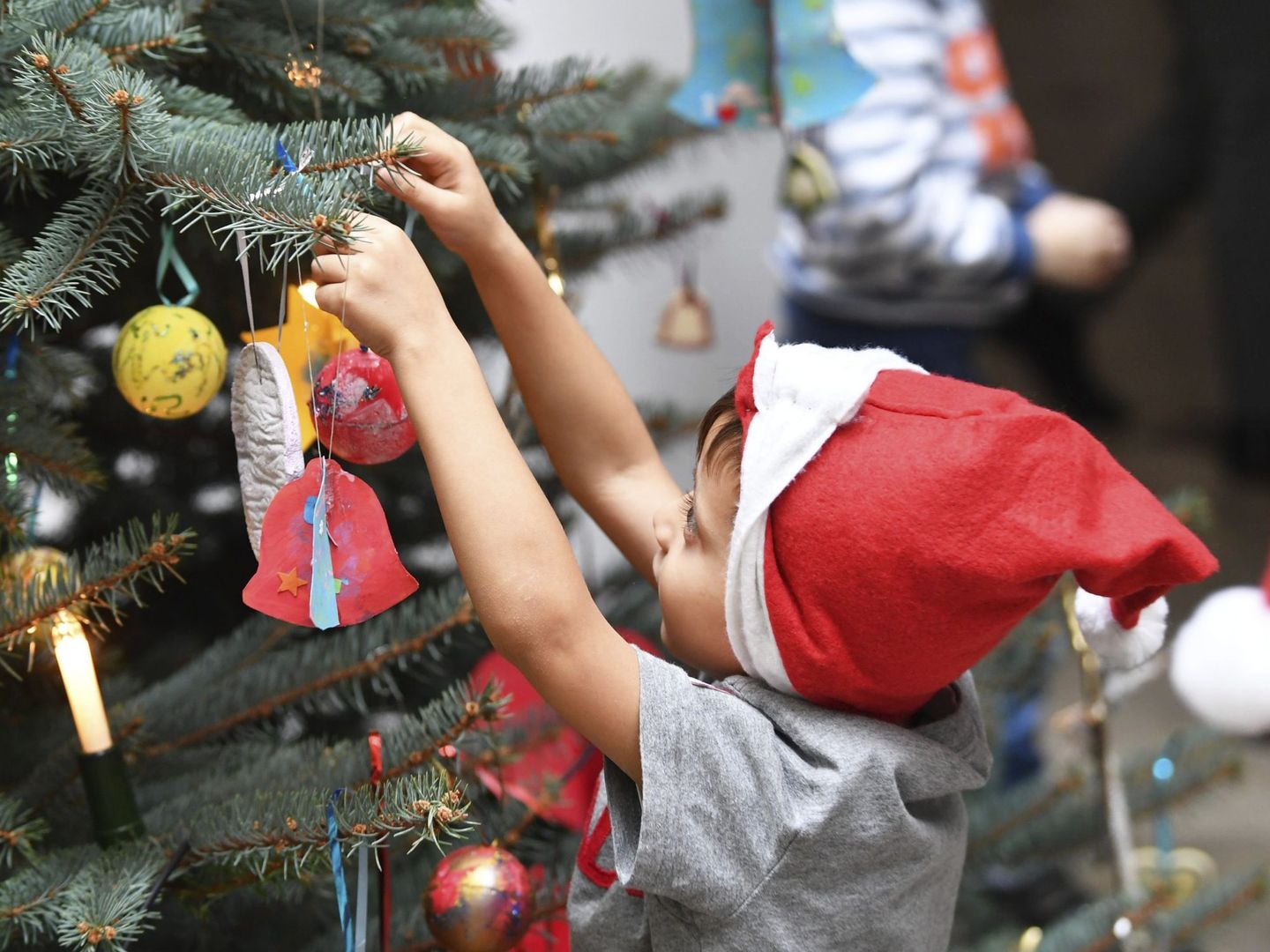 Un niño adorna un árbol de Navidad en una escuela infantil. (EFE)