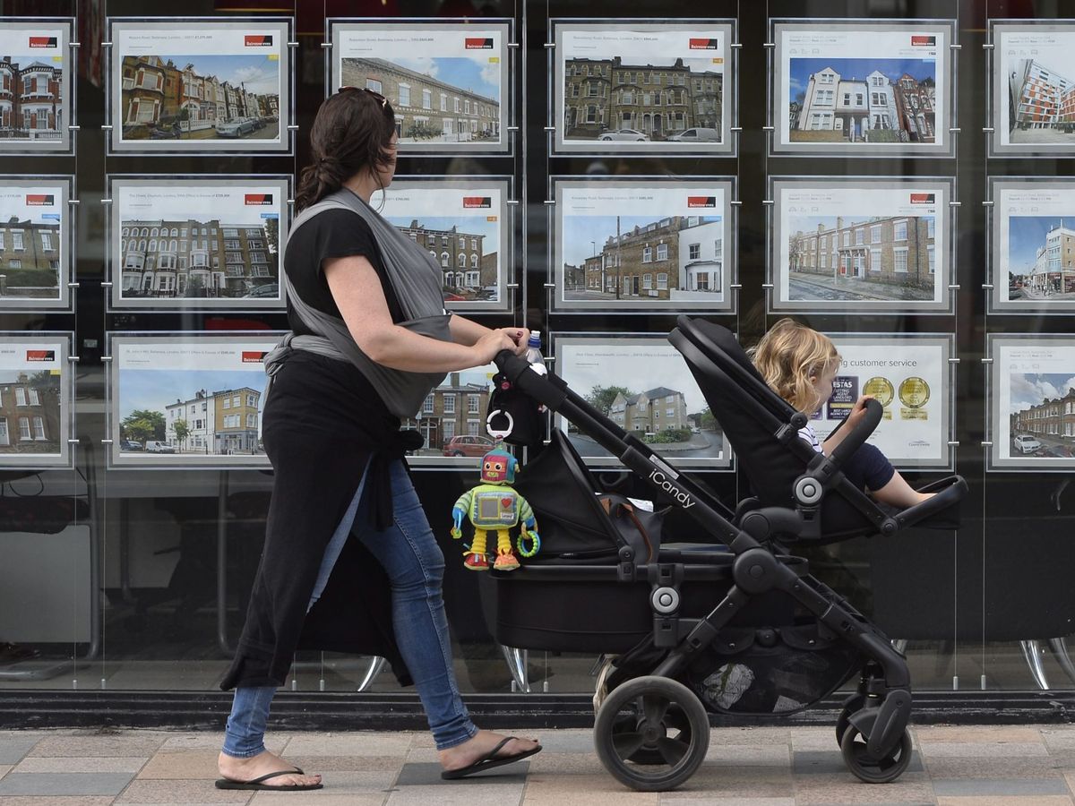 Foto: Una madre observa los anuncios de una agencia inmobiliaria. (EFE)