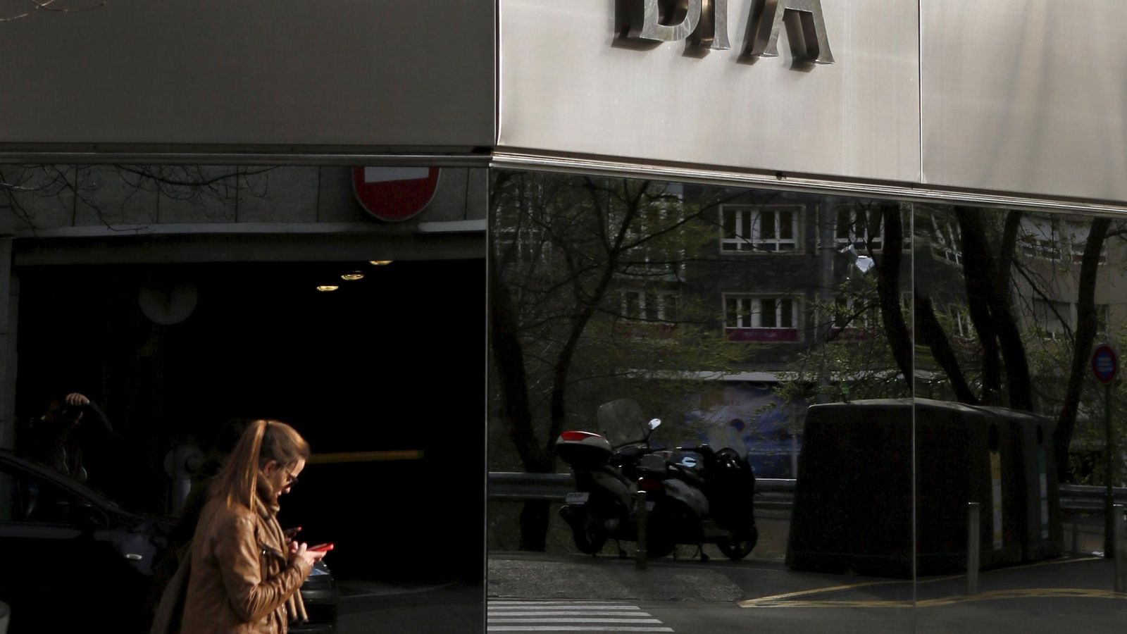 Foto: A woman looks at her mobile phone as she walks past a BPA office in Andorra la Vella