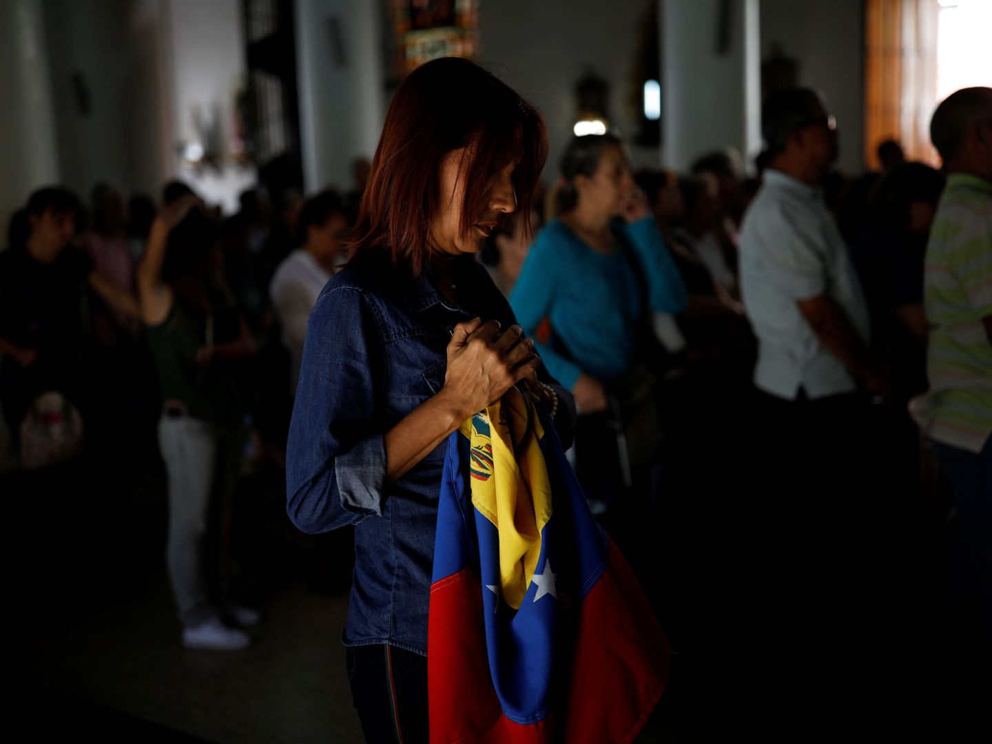Una simpatizante de Juan Guaidó sostiene una bandera de Venezuela durante una misa en Caracas. (Reuters)