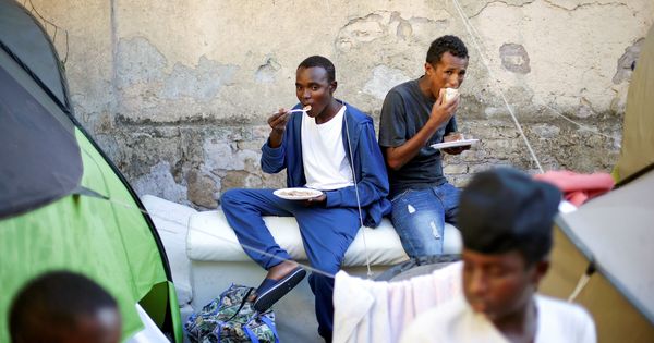 Foto: Un grupo de inmigrantes come alimentos proporcionados por voluntarios en un campamento improvisado en el centro de Roma, en agosto de 2016. (Reuters)