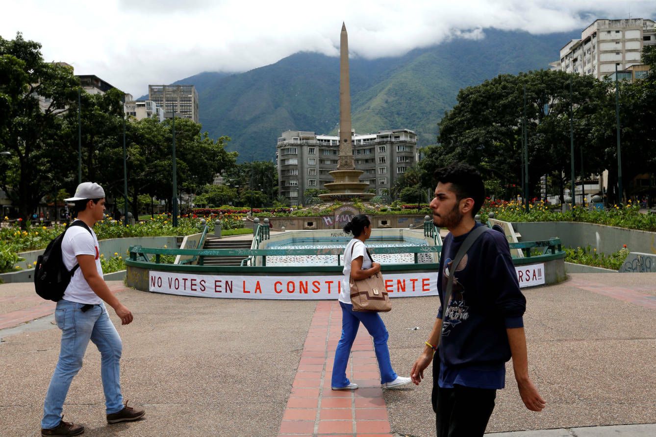 Habitantes de Caracas pasan por delante de una pancarta llamando al boicot electoral, el 26 de julio de 2017. (Reuters)