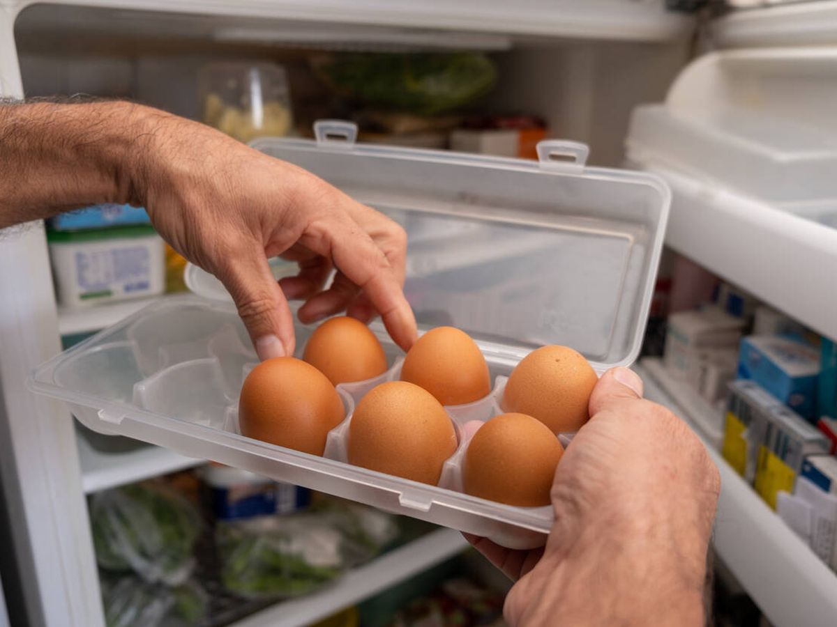 Foto: Un hombre metiendo huevos al frigorífico (iStock)