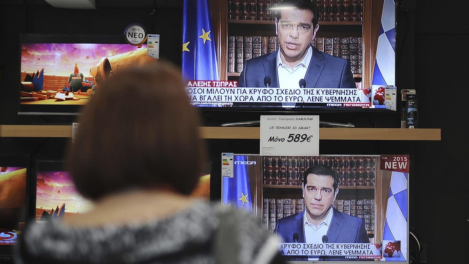 Foto: Una mujer observa en una tienda el discurso televisado del primer ministro griego, Alexis Tsipras en Atenas. (EFE)