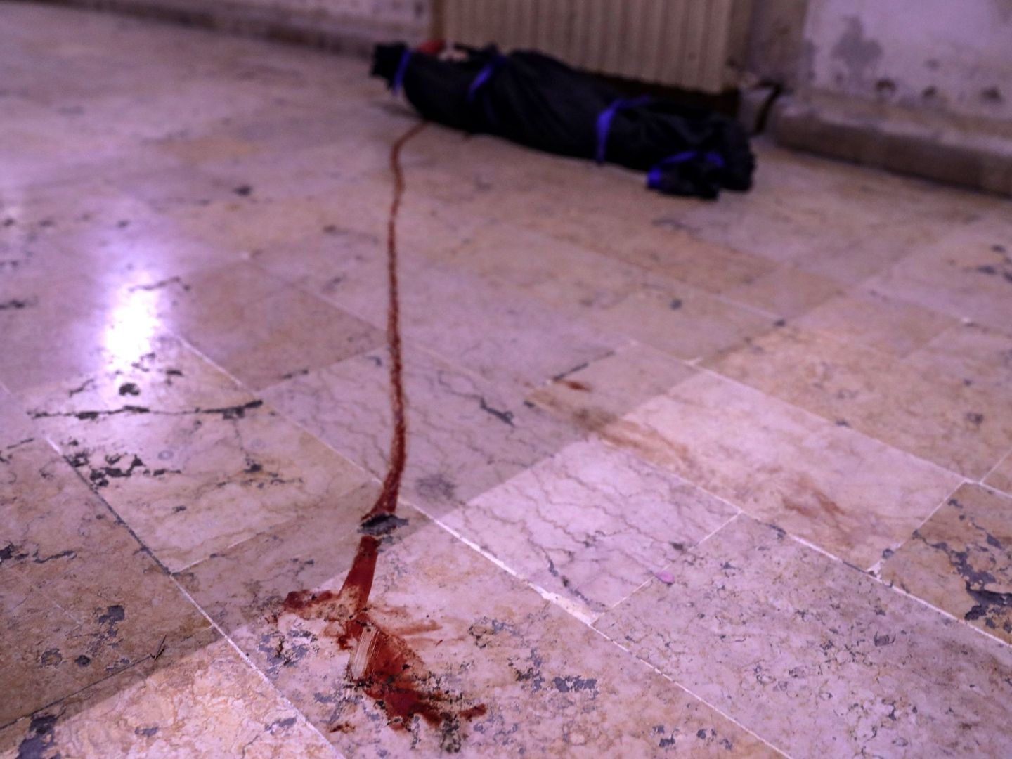 El cuerpo sin vida de una niña permanece cubierto con una manta en una morgue de Duma. (EFE)