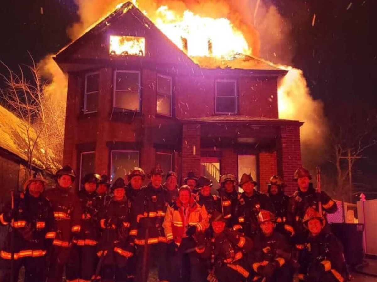Foto: Los 18 miembros del cuerpo de bomberos de Detroit, posando sonrientes mientras la casa arde a su espalda (Foto: Twitter)