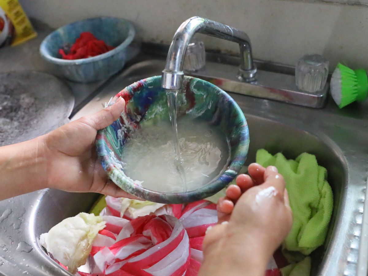 Foto: Una mujer lava arroz sobre el fregadero de su cocina (EFE/Gustavo Amador)