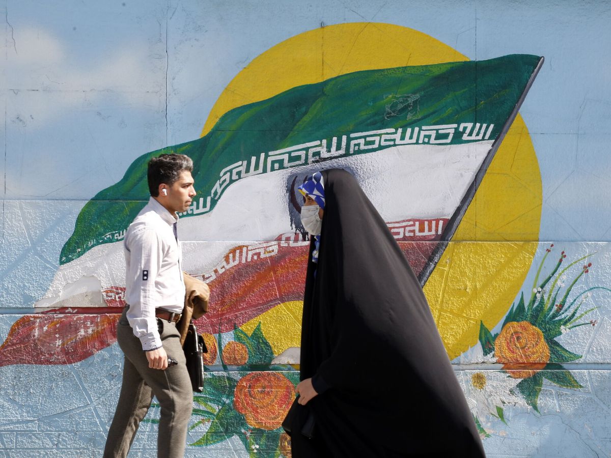 Foto: Una mujer iraní pasa por delante de un grafiti con la bandera de Irán. (EFE/EPA/Abedin Taherkenareh)