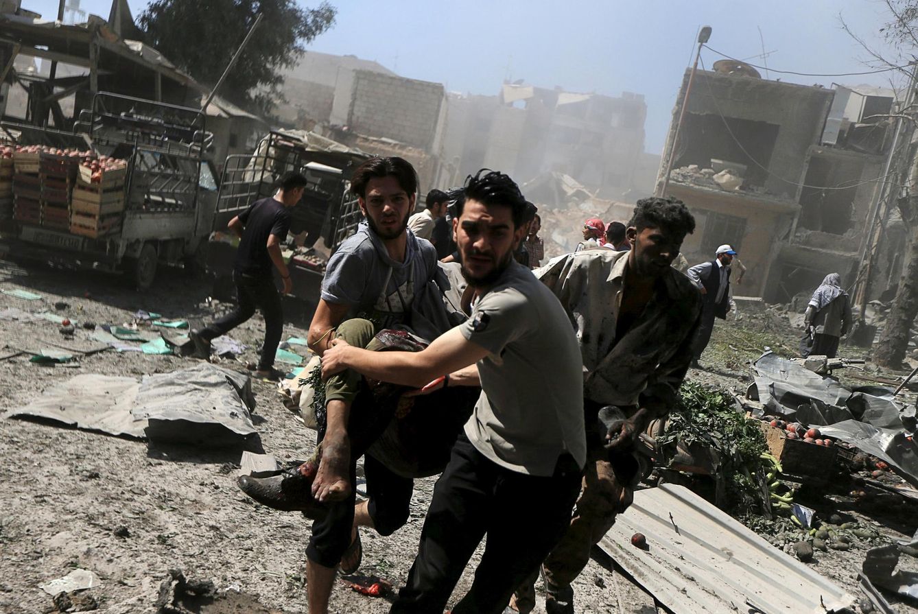 Unos sirios transportan a un hombre herido en un ataque aéreo de las fuerzas de Asad contra un mercado en Douma, Damasco. (Reuters)