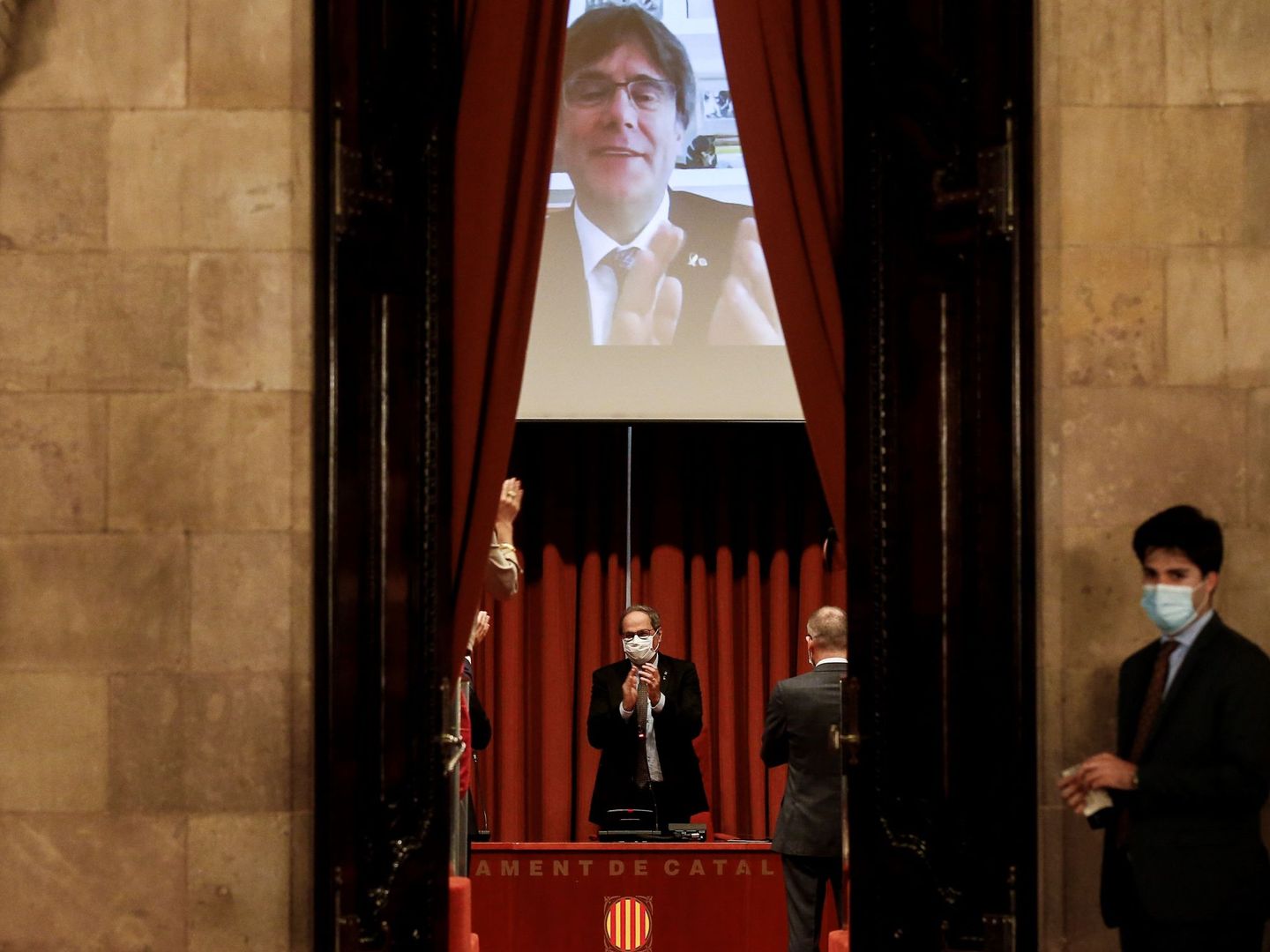 El expresidente de la Generalitat, Quim Torra, recibe el aplauso del expresidente Carles Puigdemont (en la pantalla). (EFE)