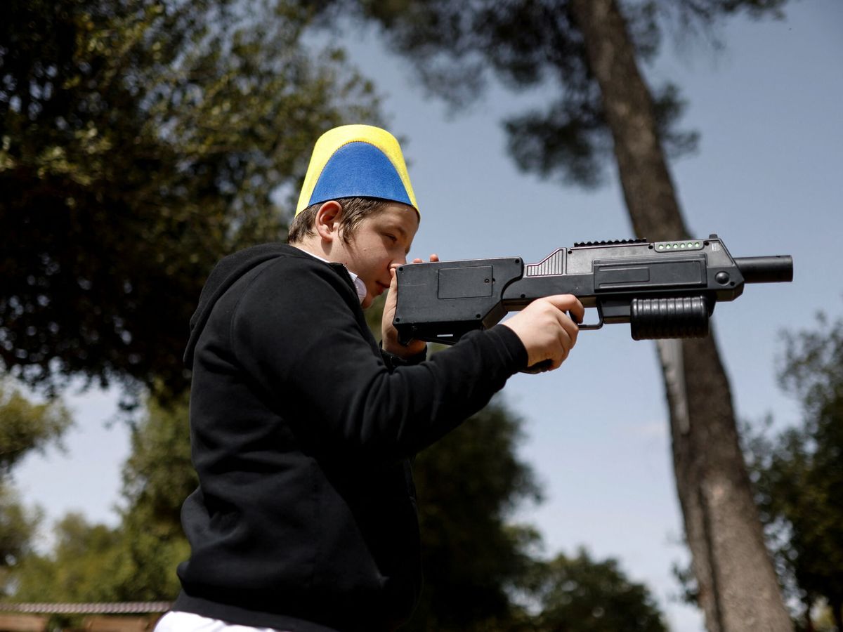 Foto: Un ucraniano judío apunta con un arma de juguete durante la fiesta del Purim tras llegar a Israel huyendo de la guerra. (Reuters/Amir Cohen)