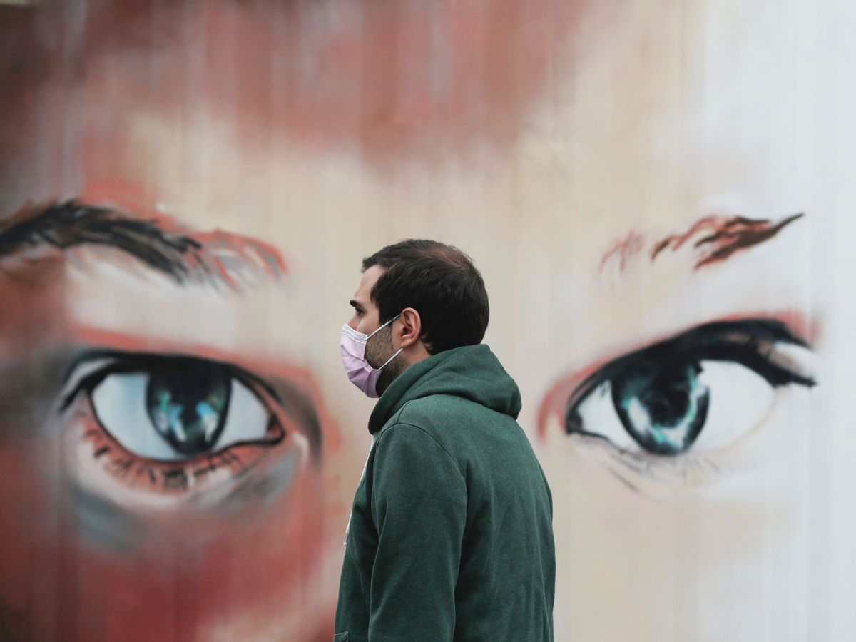 Foto: Un hombre porta una mascarilla frente a un mural. (Reuters)