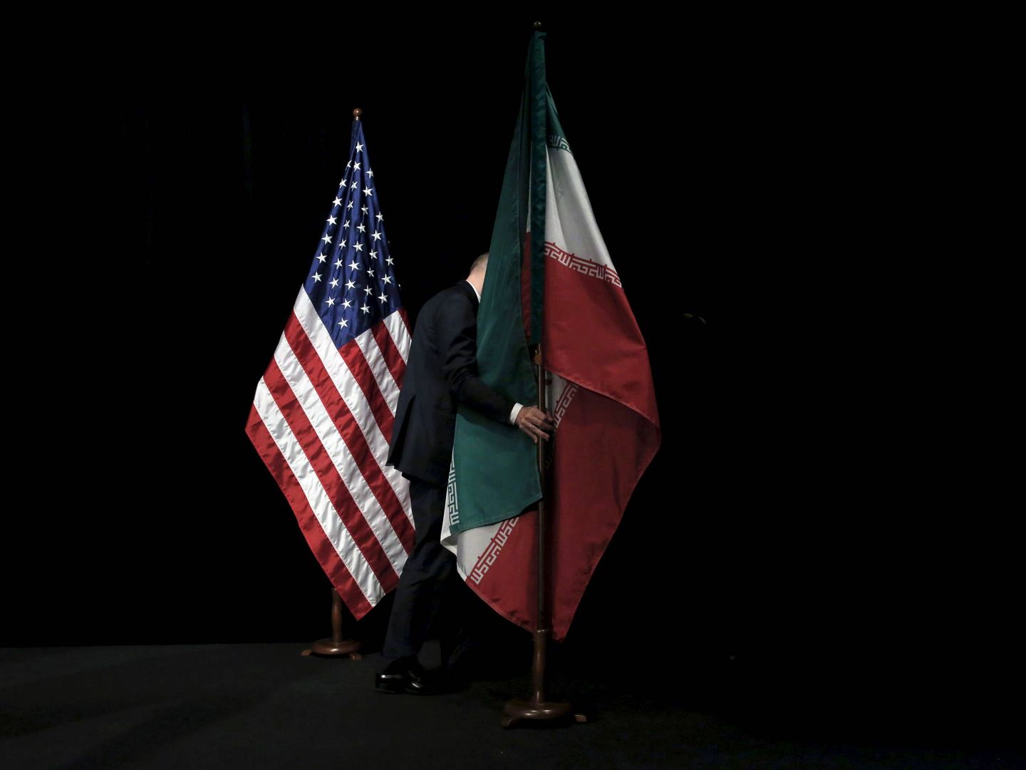 Un trabajador retira una bandera de Irán tras una cumbre sobre el acuerdo nuclear, en Viena, el 14 de julio de 2015. (Reuters) 