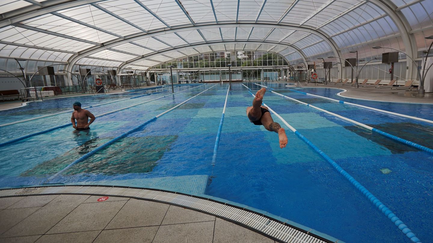 Dos usuarios de la piscina cubierta usan sus instalaciones manteniendo la distancia de seguridad entre los carriles (EFE)